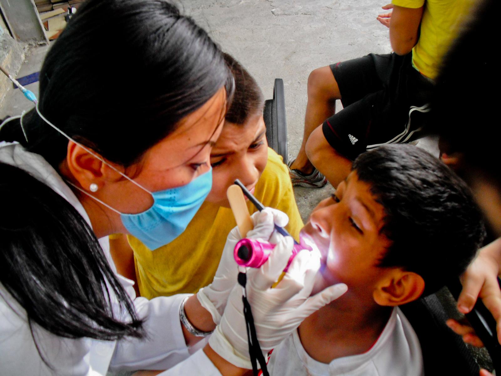 A female Dentistry intern examines a young boy's mouth during a medical outreach in Mexico. A Projects Abroad intern examines a young local boy during a medical outreach on her Dentistry internship in Mexico.